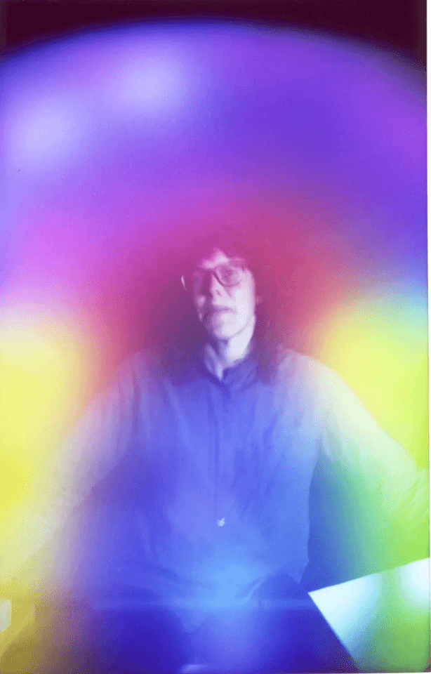 Aura portrait of a person in a dark shirt wrapped in a vivid rainbow aura of magenta, blue and yellow