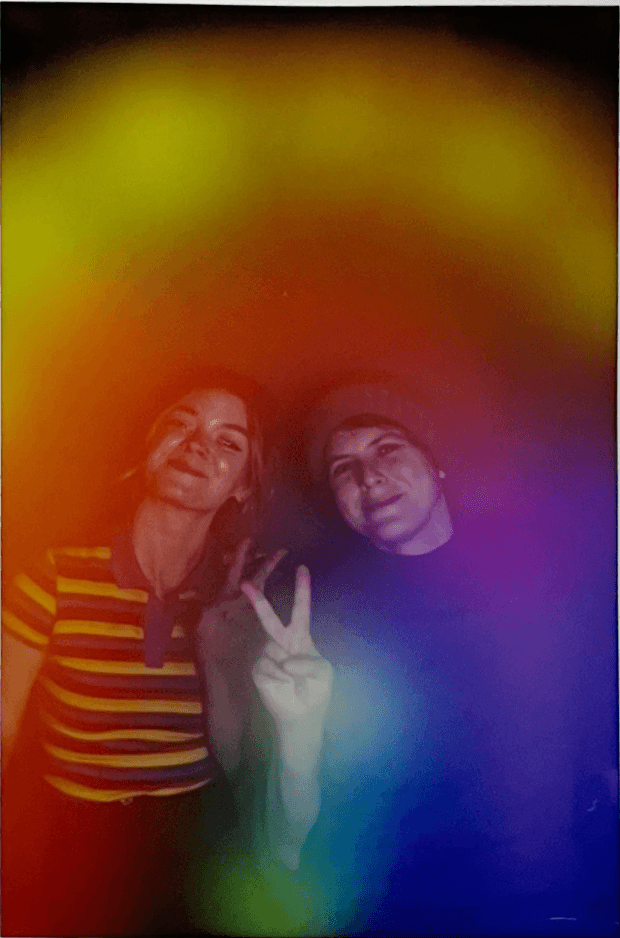 Aura portrait of two friends, one flashing a peace sign, glowing in warm orange-to-violet light
